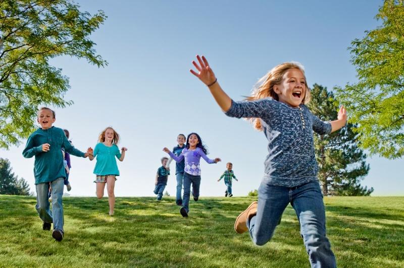 Children running down a grass hill