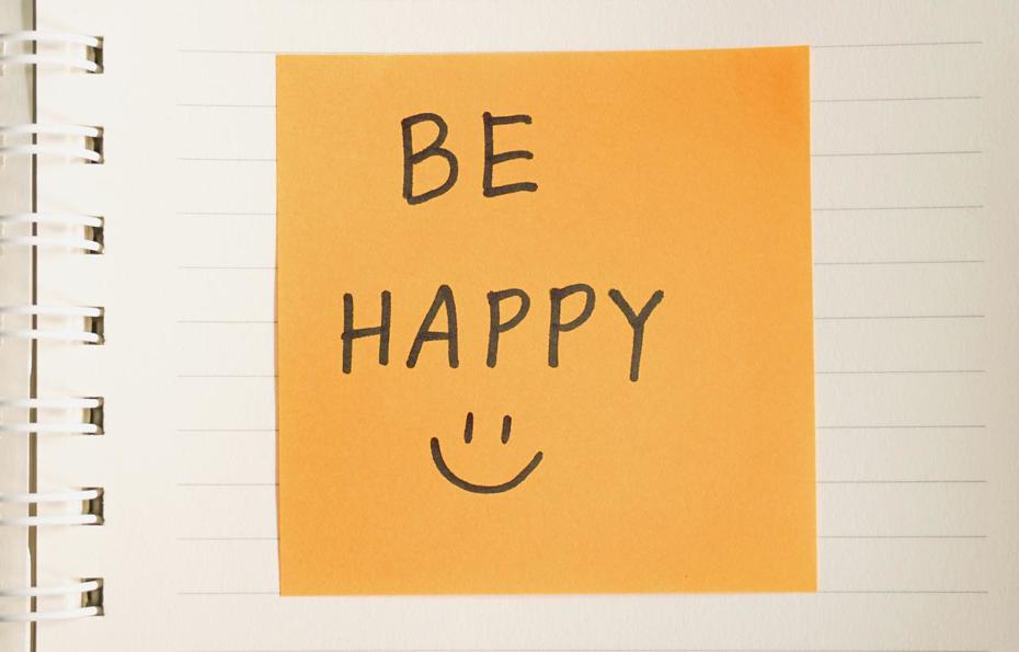 A post-it note with the words be happy and a smiley face