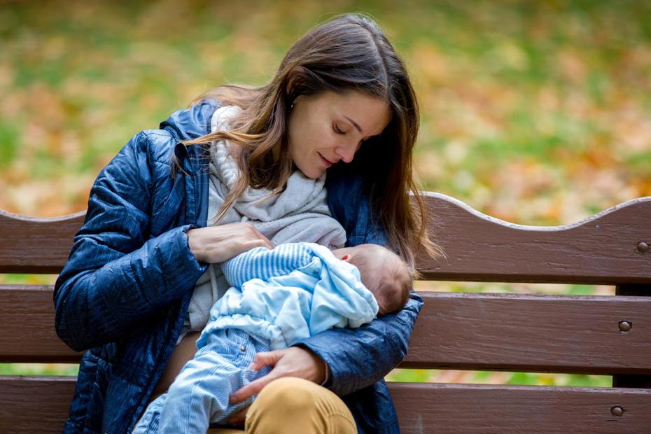 Women breastfeeding on a park bench