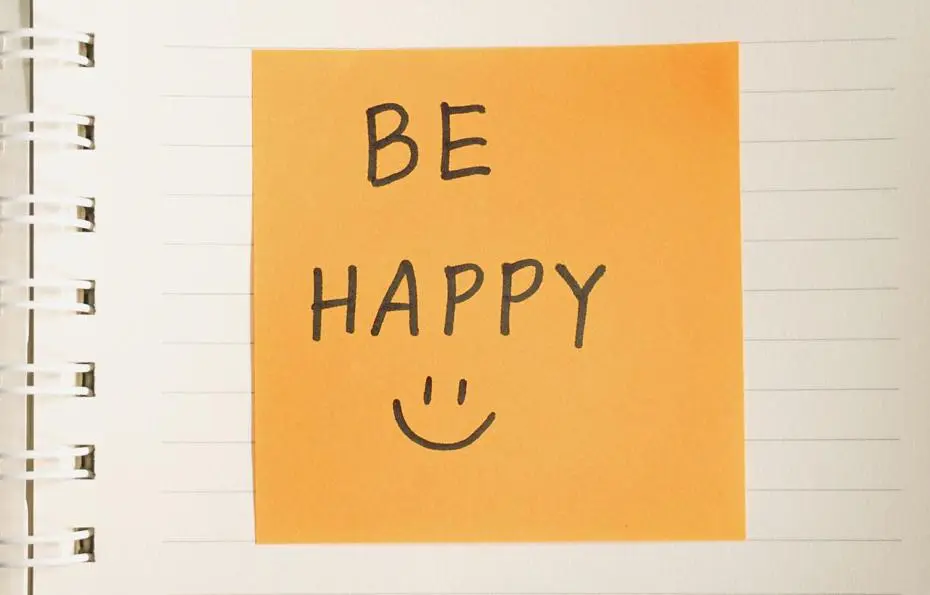 A post-it note with the words be happy and a smiley face